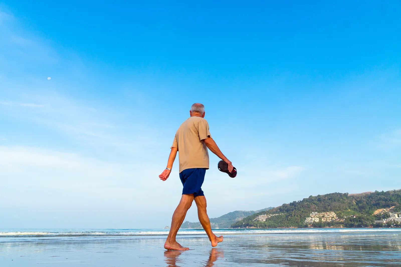 Un homme retraité marche au bord de la mer, symbole de temps retrouvé et de projets futurs