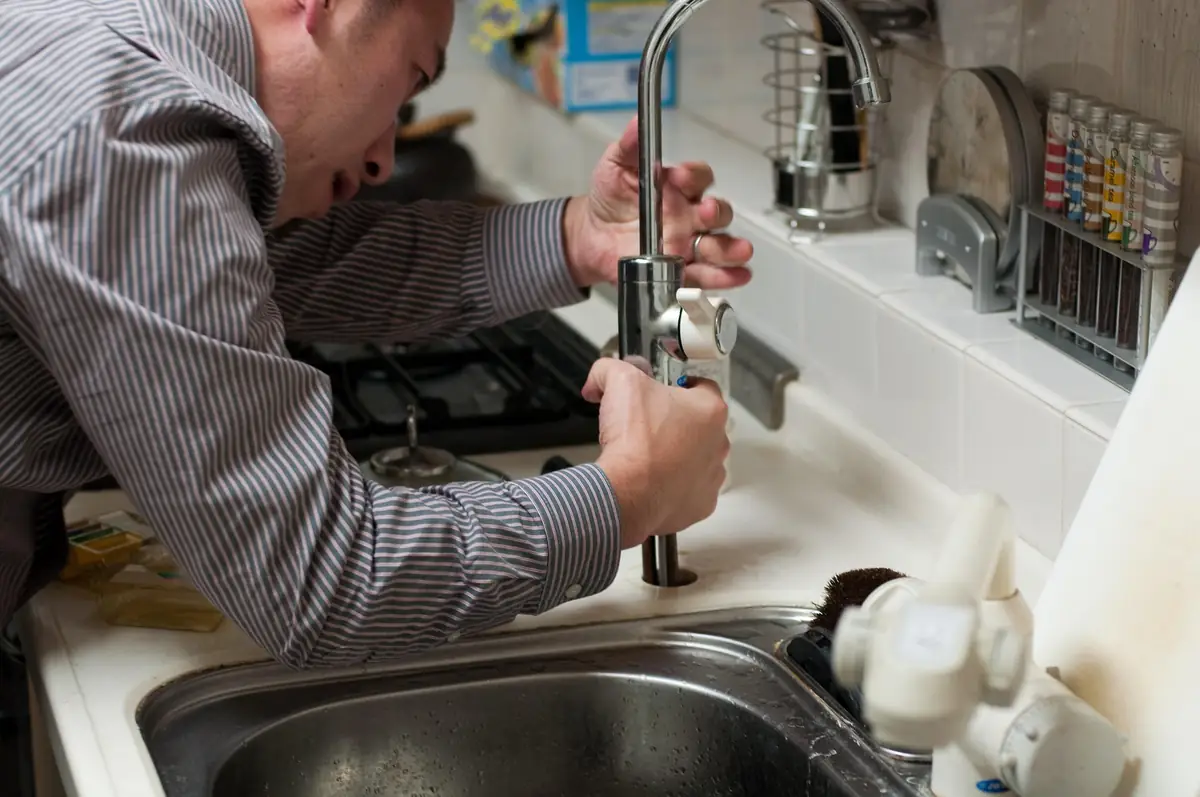 Artisan plombier intervenant sur une installation chez un client
